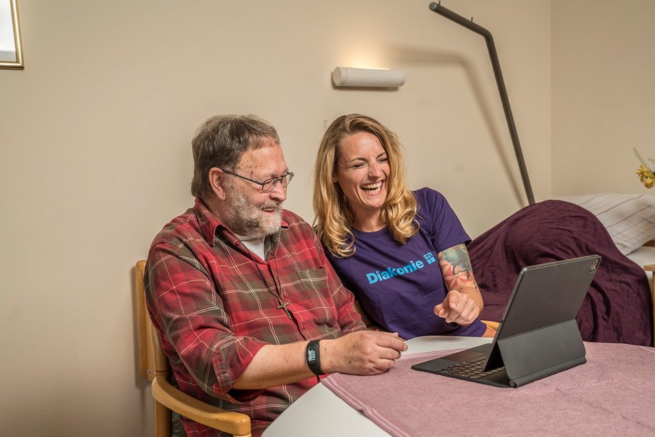 Junge Frau und älterer Mann schauen gemeinsam auf ein Tablet 