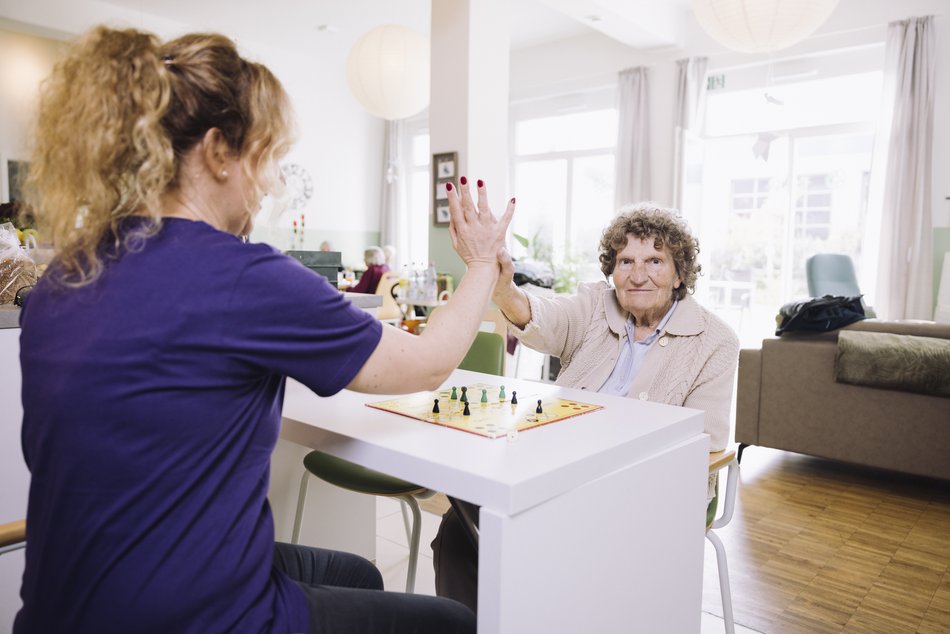 Junge Frau und ältere Frau machen High Five (schlagen in die Hände)